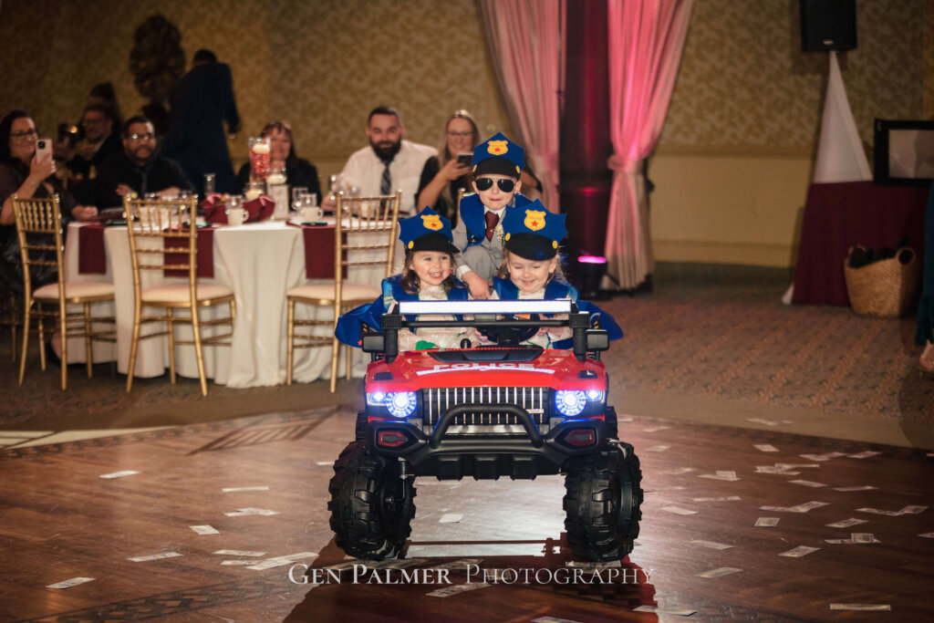 Cute ring bearer and flower girls on a truck with police caps at the reception