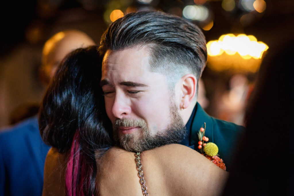Groom embracing wedding guest at Porta Asbury Park.