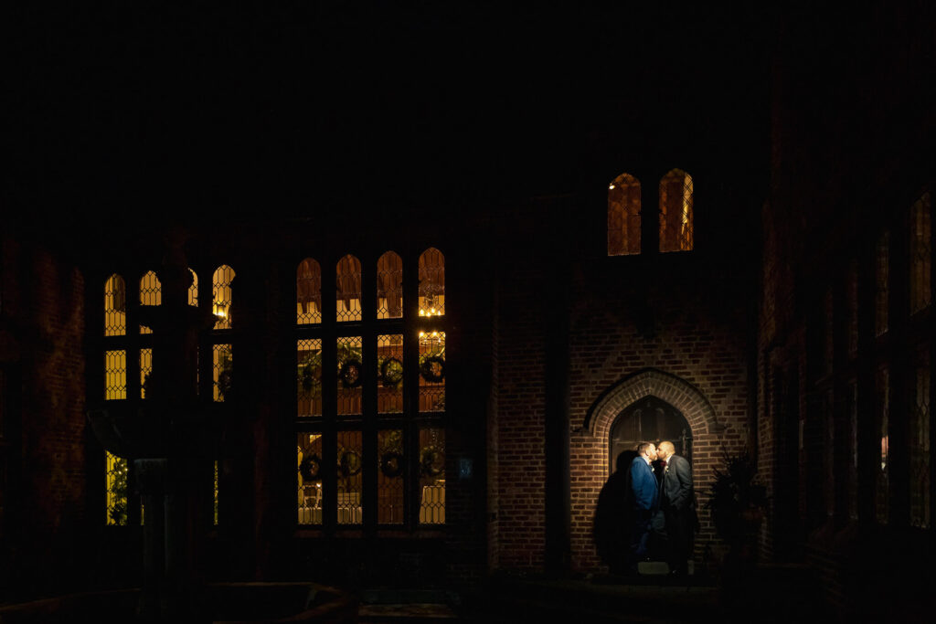 Grooms kissing at night at Aldie Mansion