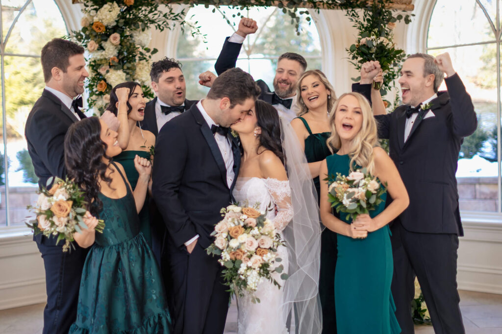 Couple kissing in front of bridesmaids and groomsmen at Nanina's In The Park