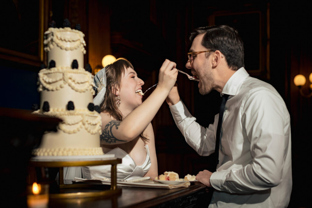Couple giving each other bites of first cake slice at Philadelphia College of Physicians